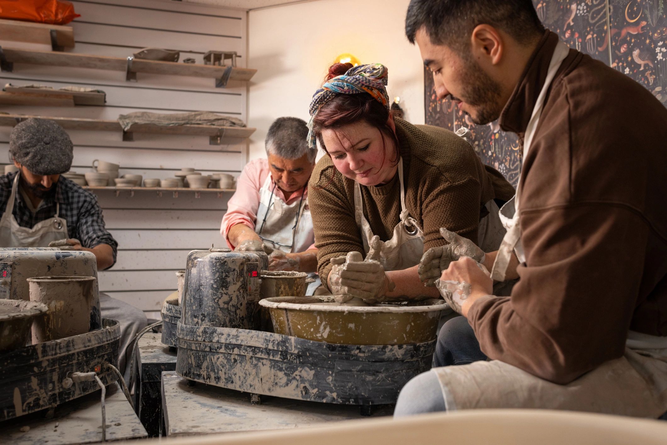 Pottery instructor helping students at the wheel in a studio